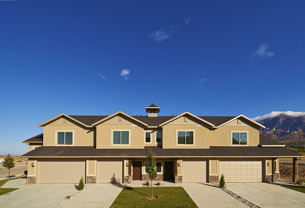 Row of two-story townhomes with attached garages and mountain views